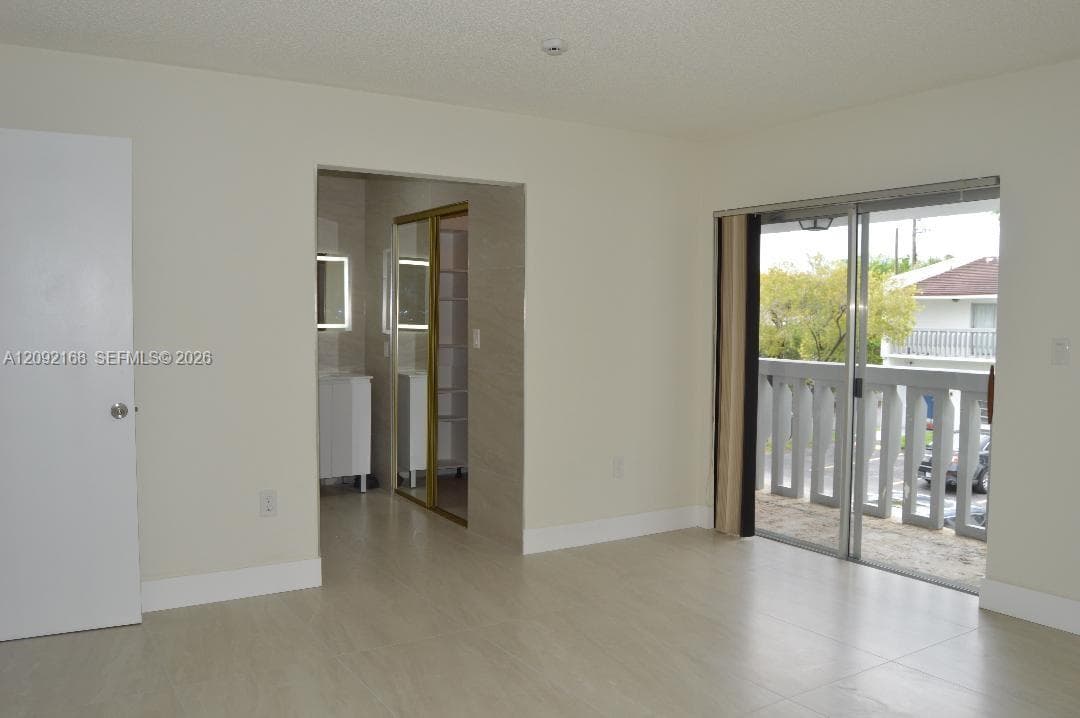 MASTER BEDROOM VIEW OF THE BALCONY AND THE ENTRANCE TO THE LARGE MASTER BATHROOM.