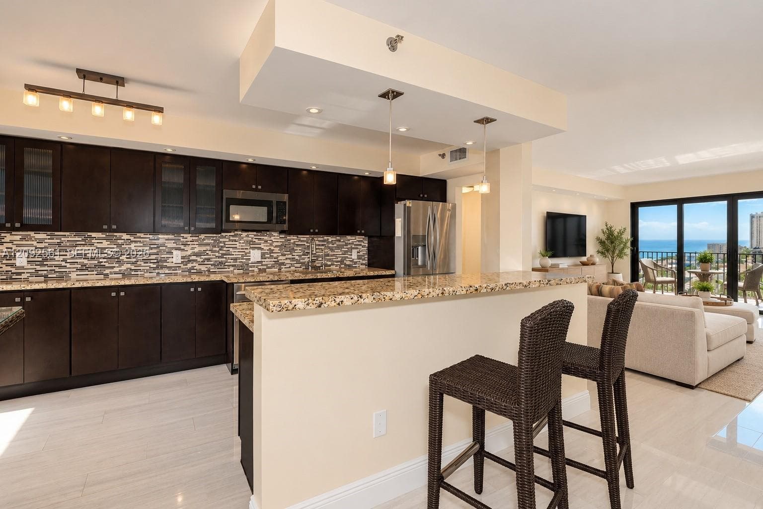 Kitchen featuring dark wood cabinetry, stone countertops, a mosaic tile backsplash, stainless steel appliances, and a breakfast bar