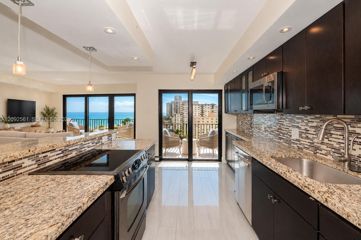 Kitchen featuring dark-finish cabinetry, natural stone countertops, a mosaic tile backsplash, recessed lighting, and stainless steel appliances