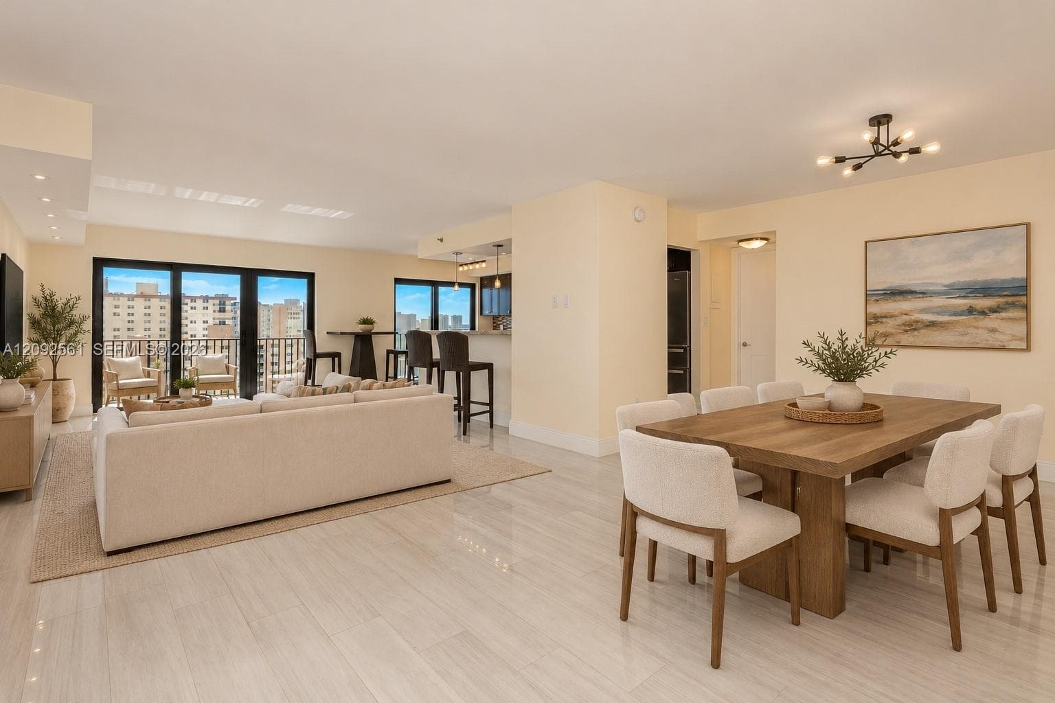 Open-concept floor plan featuring large format light-toned tile flooring, recessed ceiling lighting, a modern multi-arm chandelier, and floor-to-ceiling glass sliding doors