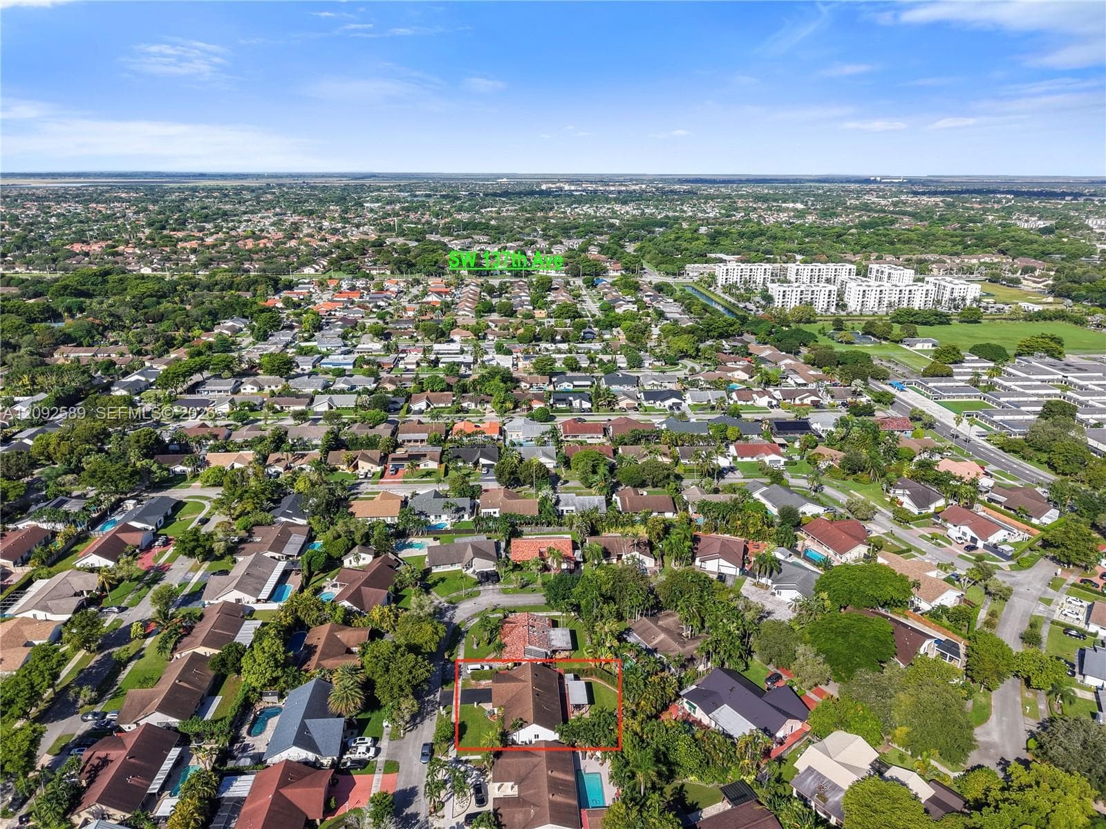 Residential neighborhood setting with mature trees and visible roadways