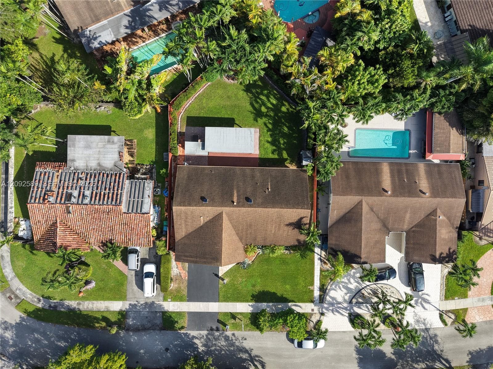 Gable roofline, paved driveway, mature landscaping, sidewalk access, and street frontage