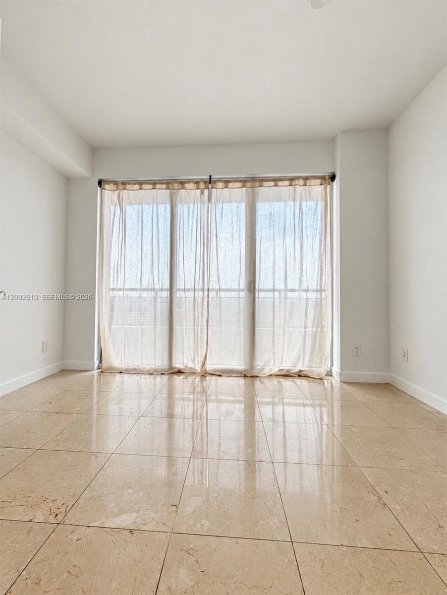 Neutral-toned large-format floor tiling and floor-to-ceiling sliding glass doors