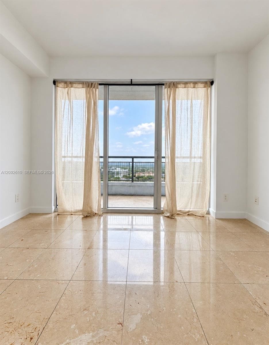 Floor-to-ceiling sliding glass doors, polished stone tile flooring, and a private balcony with a metal railing