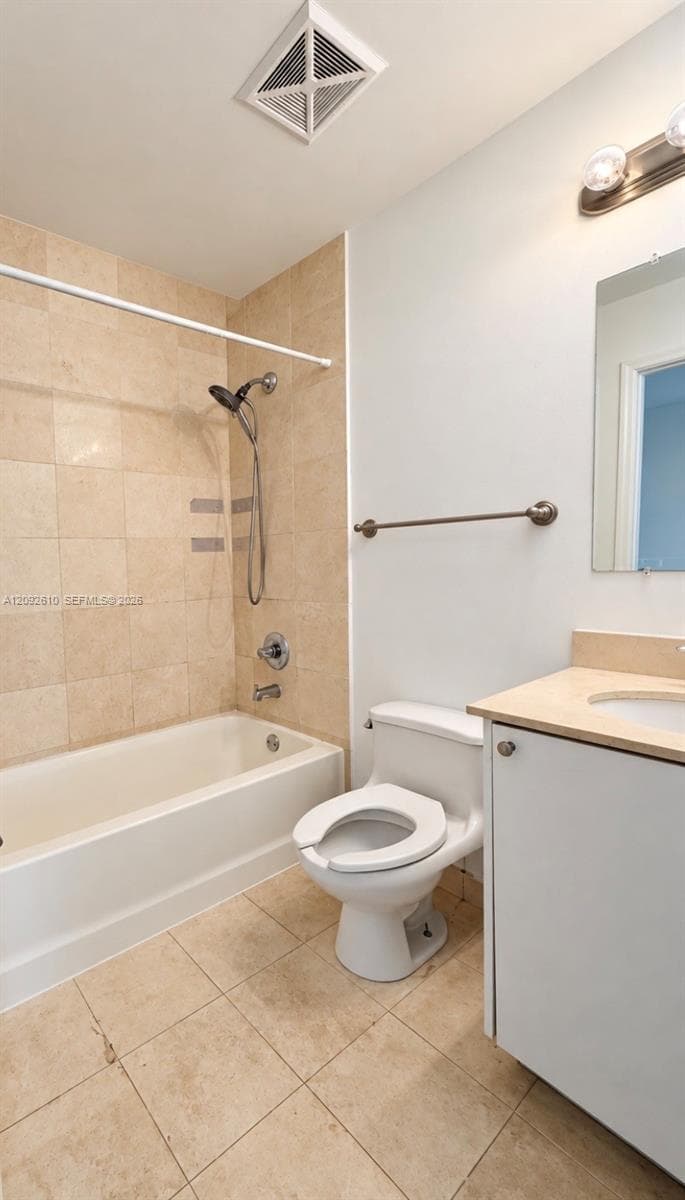 Bathroom featuring a tub-shower combination with floor-to-ceiling tile surround, stone-top vanity, wall-mounted mirror, and tile flooring