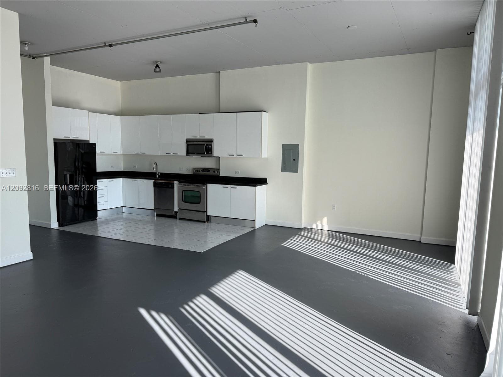 Open-concept living area featuring a kitchen with white cabinetry and dark countertops