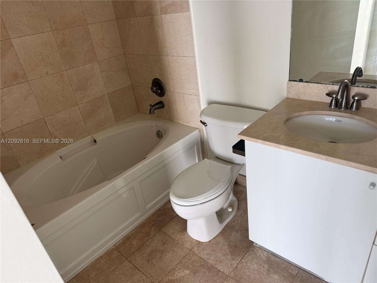 Integrated bathtub with panel detailing, tiled shower surround, recessed vanity with countertop, undermount sink, and brushed nickel fixtures