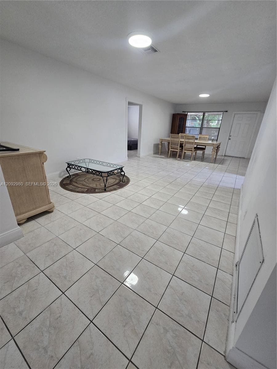 Open interior space featuring light-toned ceramic tile flooring, neutral walls, and flush-mount ceiling lighting
