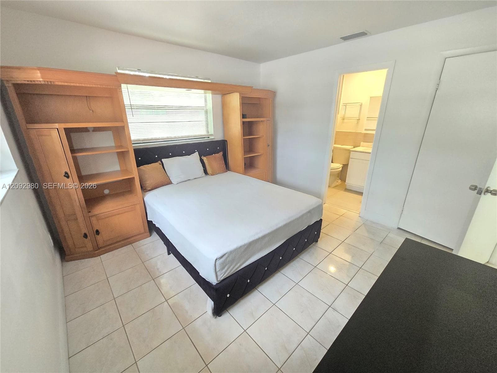 Room featuring tile flooring and built-in wood cabinetry with shelving