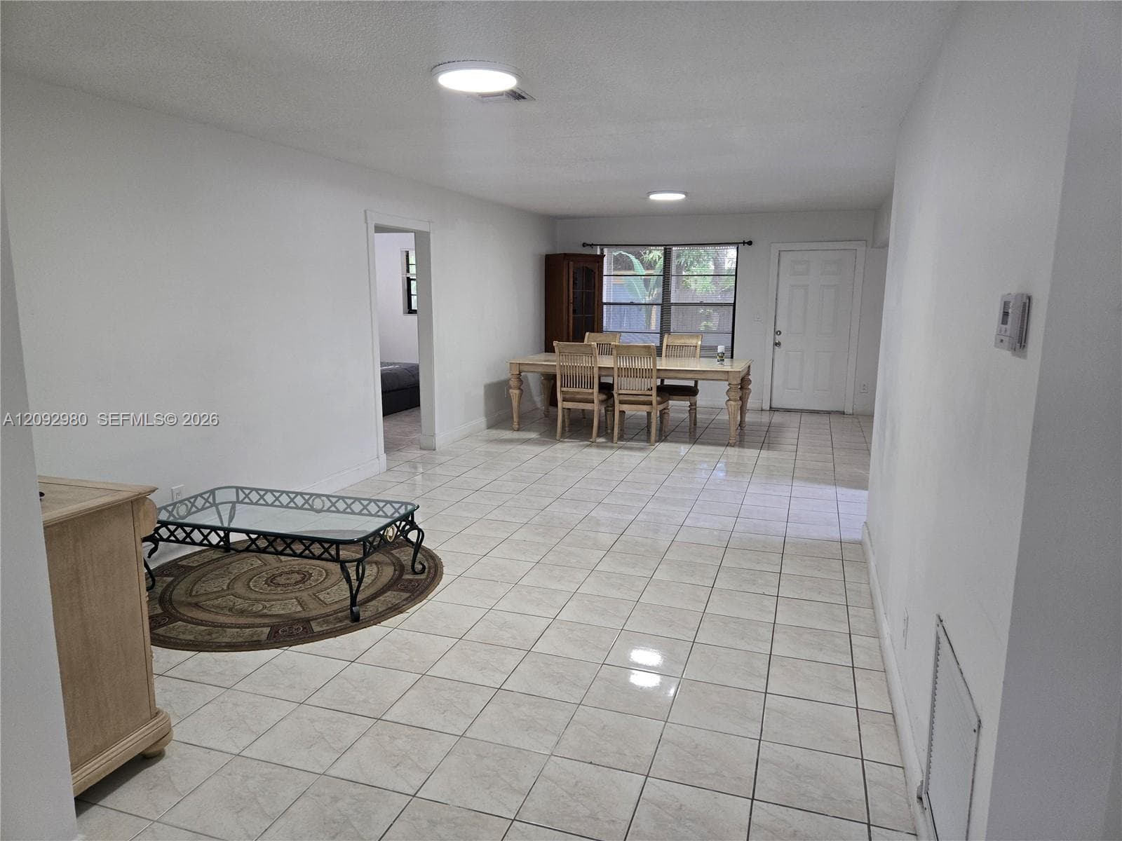 Open interior featuring neutral wall paint, consistent ceramic tile flooring, flush-mount ceiling lighting, and multi-pane windows