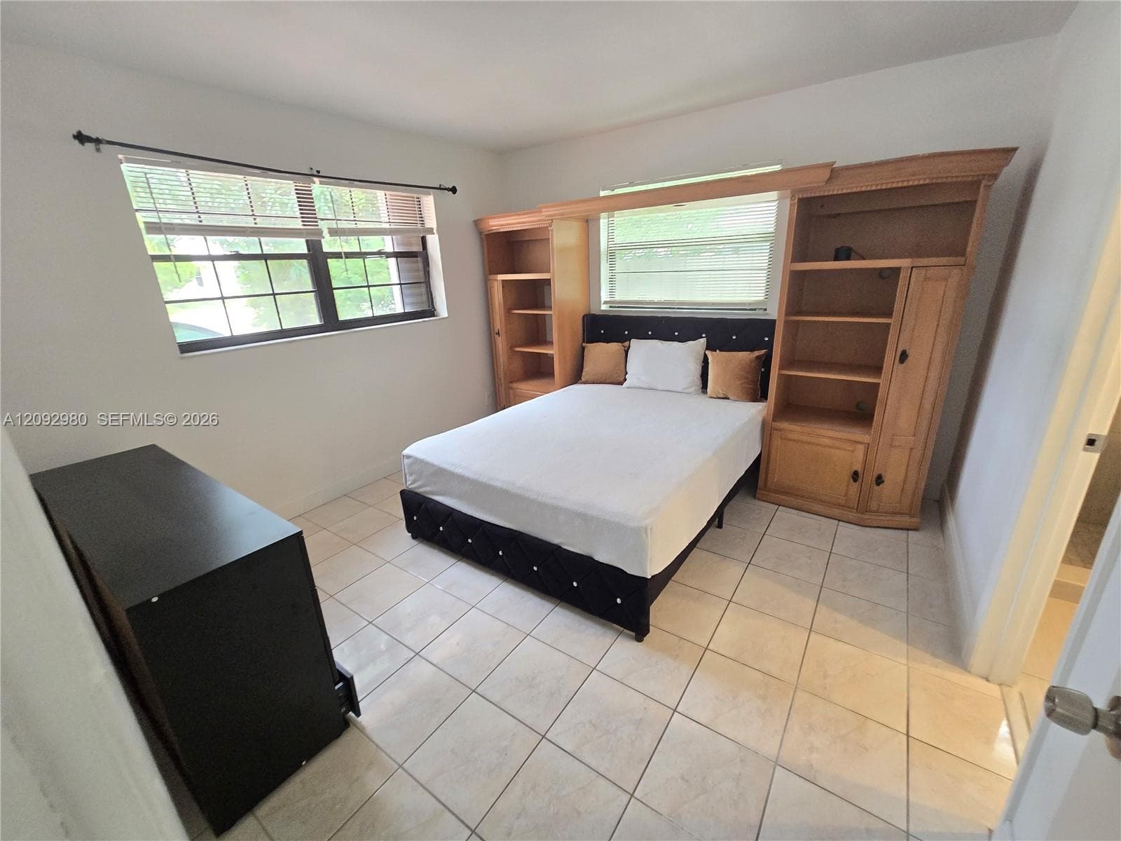 Light-filled room with ceramic tile flooring, built-in wooden cabinetry, and large windows with horizontal blinds