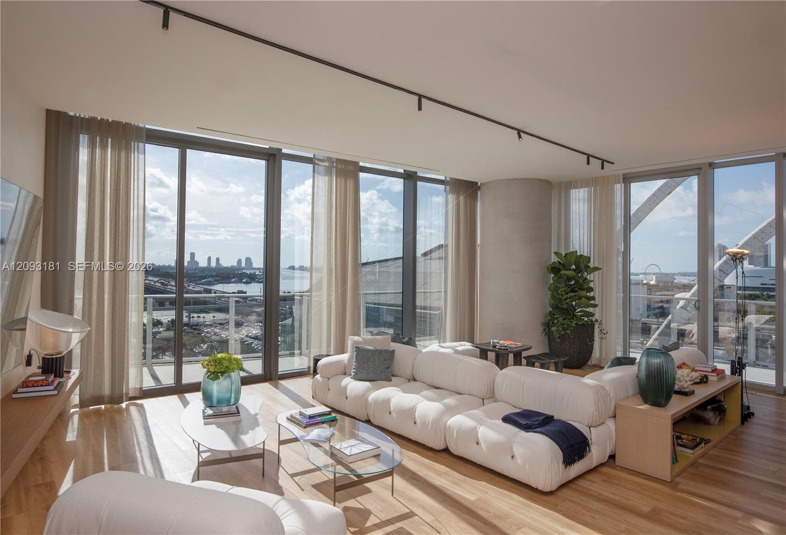 Floor-to-ceiling windows, wood-finish flooring, exposed concrete structural column, and ceiling-mounted track lighting