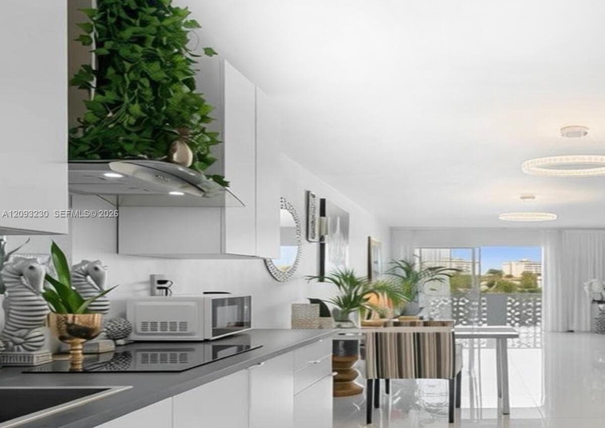 Sleek kitchen featuring white cabinetry, integrated cooktop, and contemporary range hood