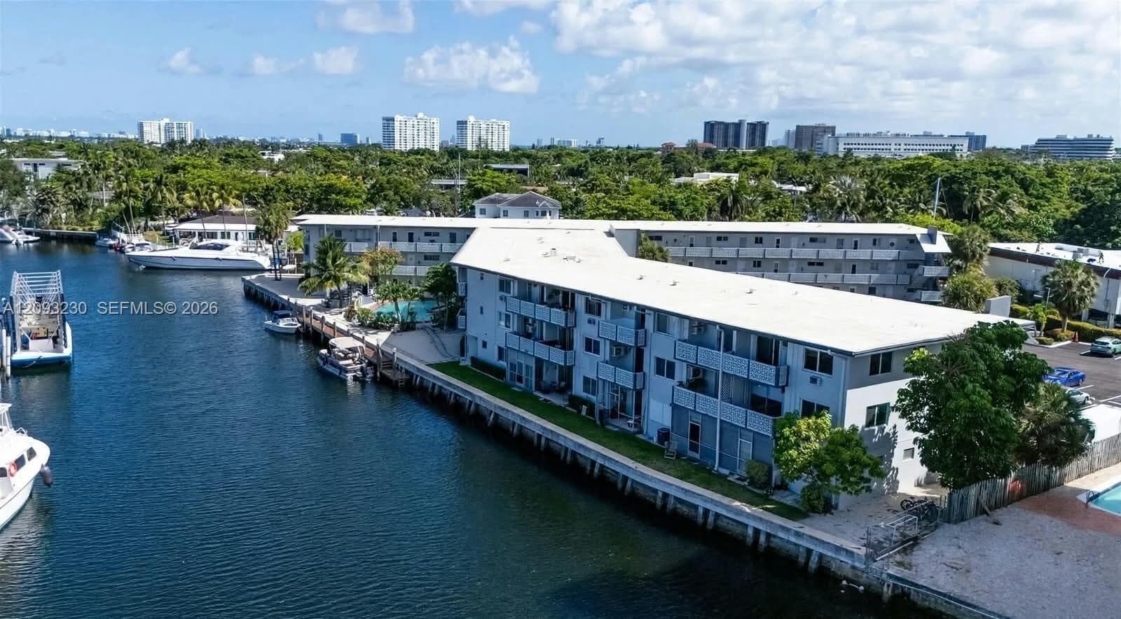 Waterfront property featuring multiple buildings, private boat docks, a swimming pool, and a paved parking area