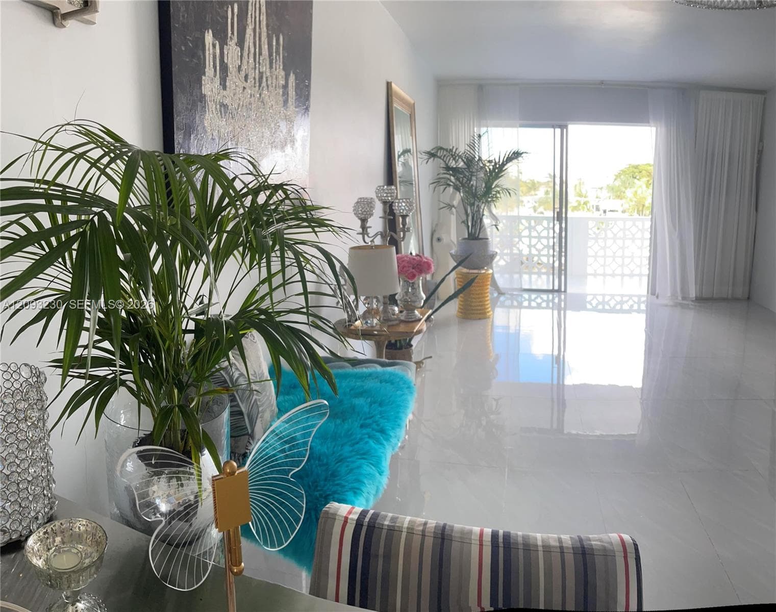 White walls with recessed lighting, reflective tile flooring, sliding glass doors, white decorative balcony railing, and white sheers