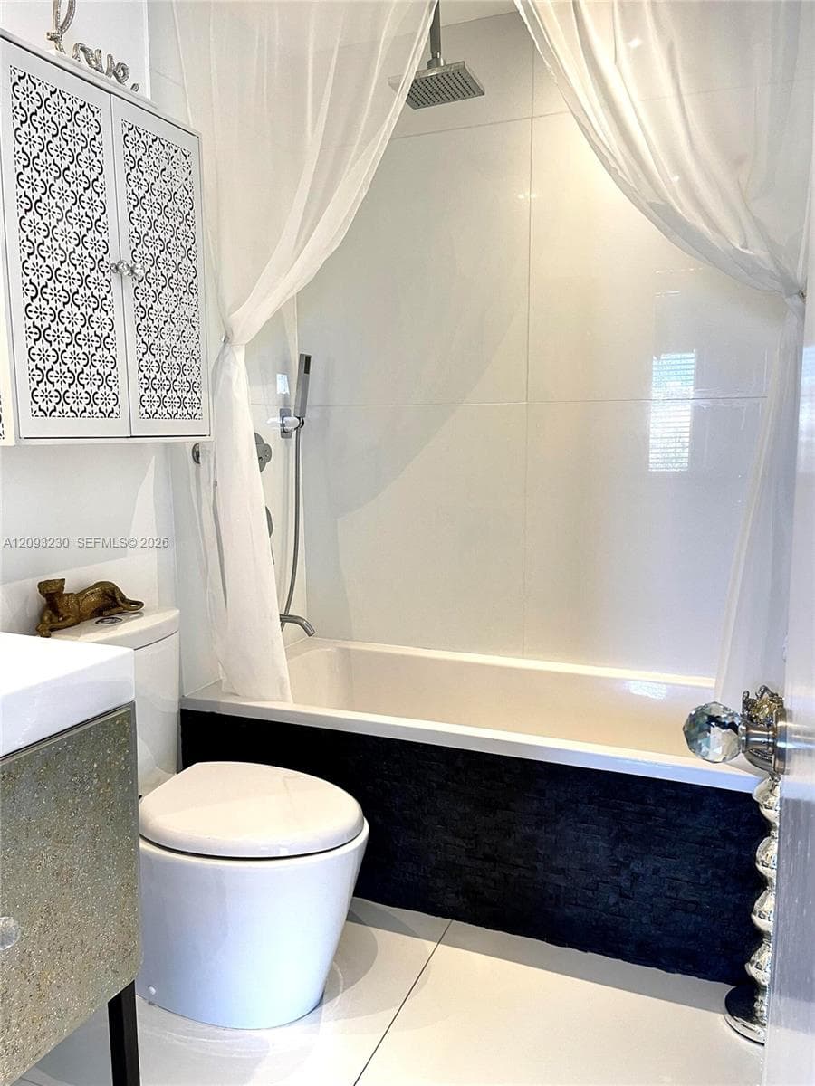 White subway tile shower surround with a rain shower head, a white bathtub, and a dark textured tub panel