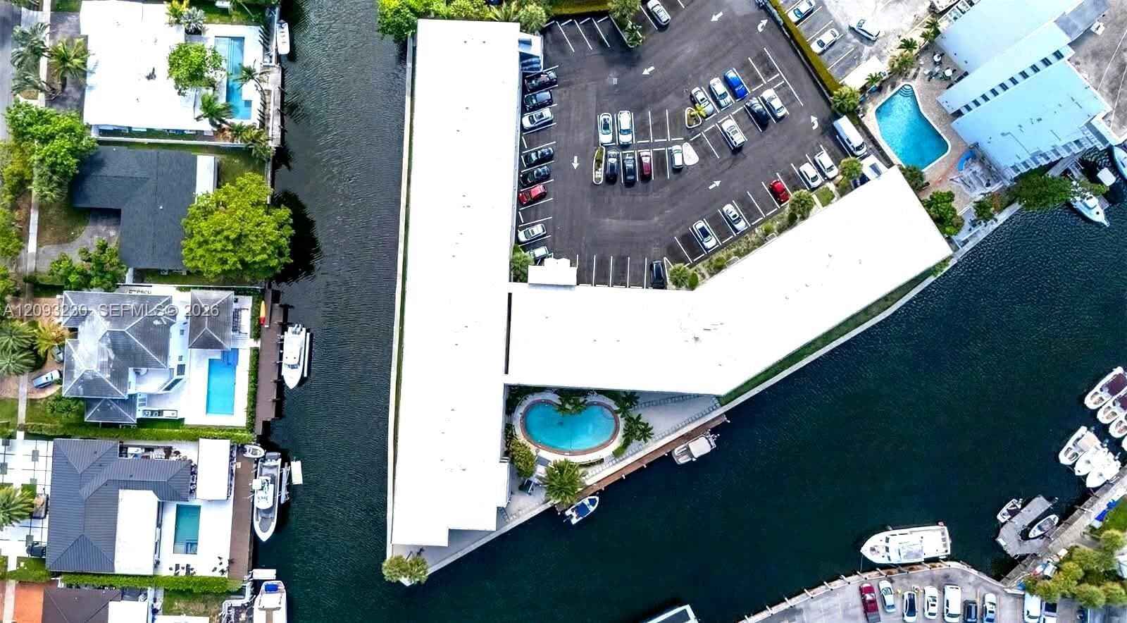 Waterfront property with direct canal access, an on-site parking lot, and a curvilinear swimming pool