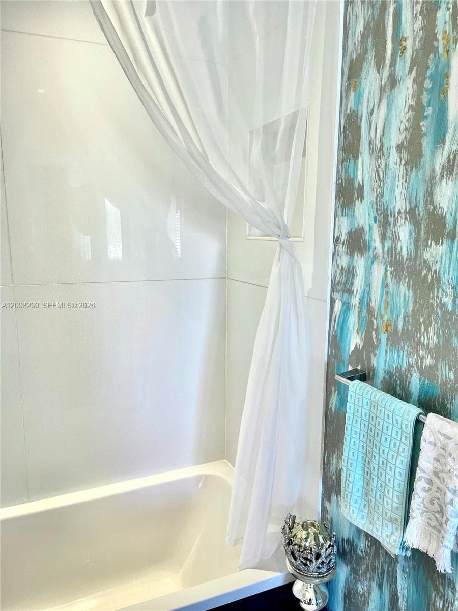 Bathtub with a white surround and a towel bar