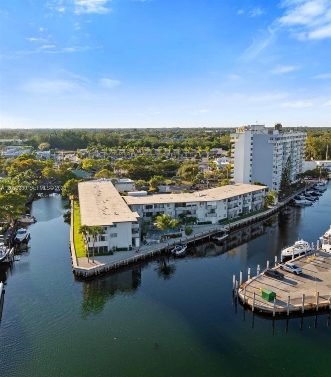 Waterfront property featuring multiple boat slips, a multi-story building, and mature landscaping