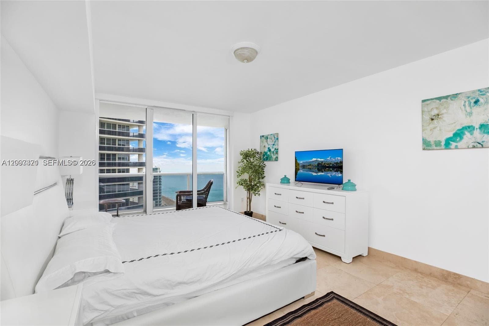 Floor-to-ceiling windows, high ceilings, light-toned tile flooring, and white walls