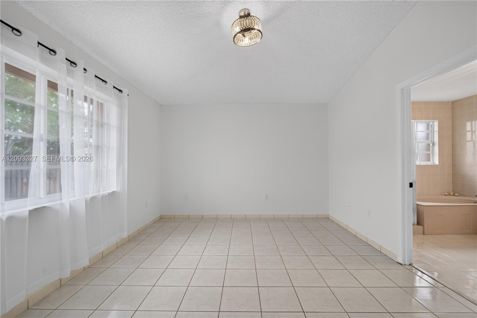 Interior space featuring ceramic tile flooring, neutral walls, large window with multi-pane glass, and a decorative semi-flush mount ceiling fixture