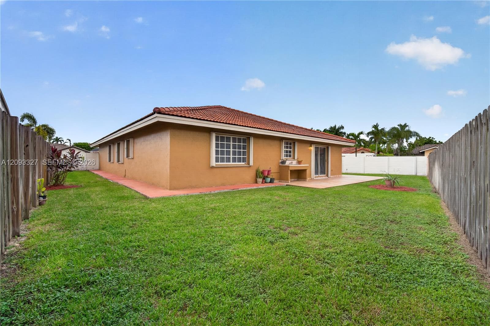 Spacious backyard featuring a concrete patio, built-in outdoor prep station, and full-perimeter wood fencing
