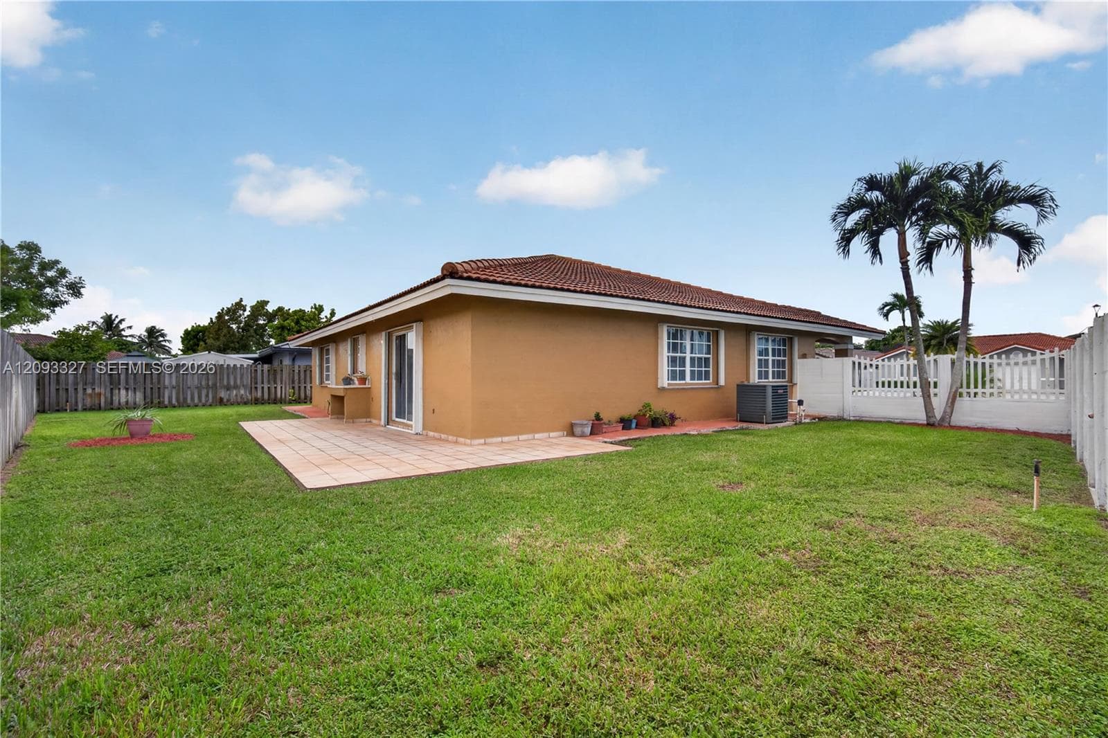 Backyard featuring a paved patio, perimeter privacy fencing, and mature palm trees