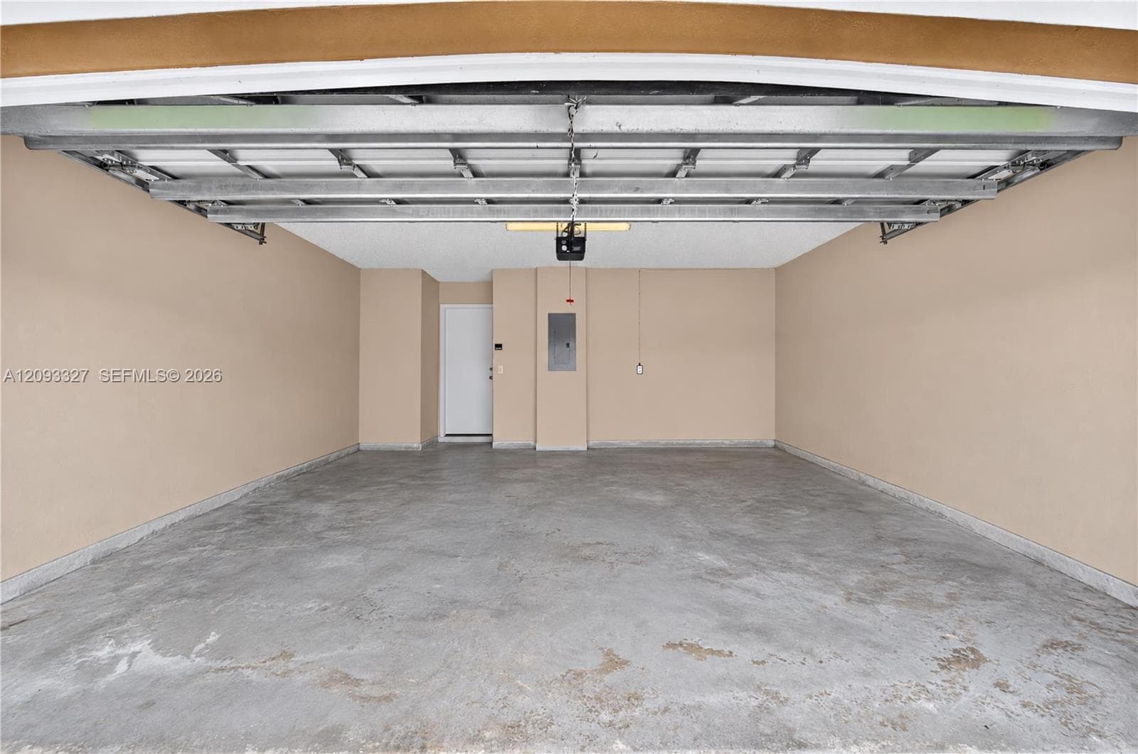 Two-car garage featuring a concrete floor, painted interior walls, overhead door opener, and a dedicated service door