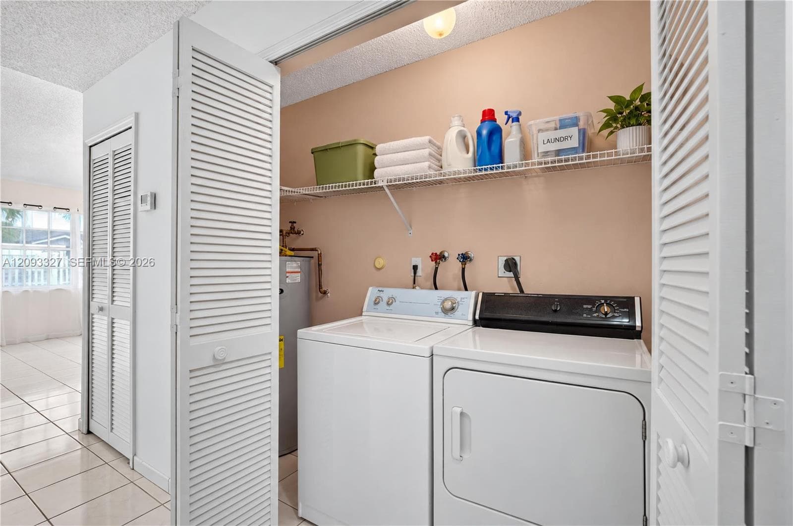 Laundry closet featuring louvered bi-fold doors, white ceramic tile flooring, and integrated wire shelving