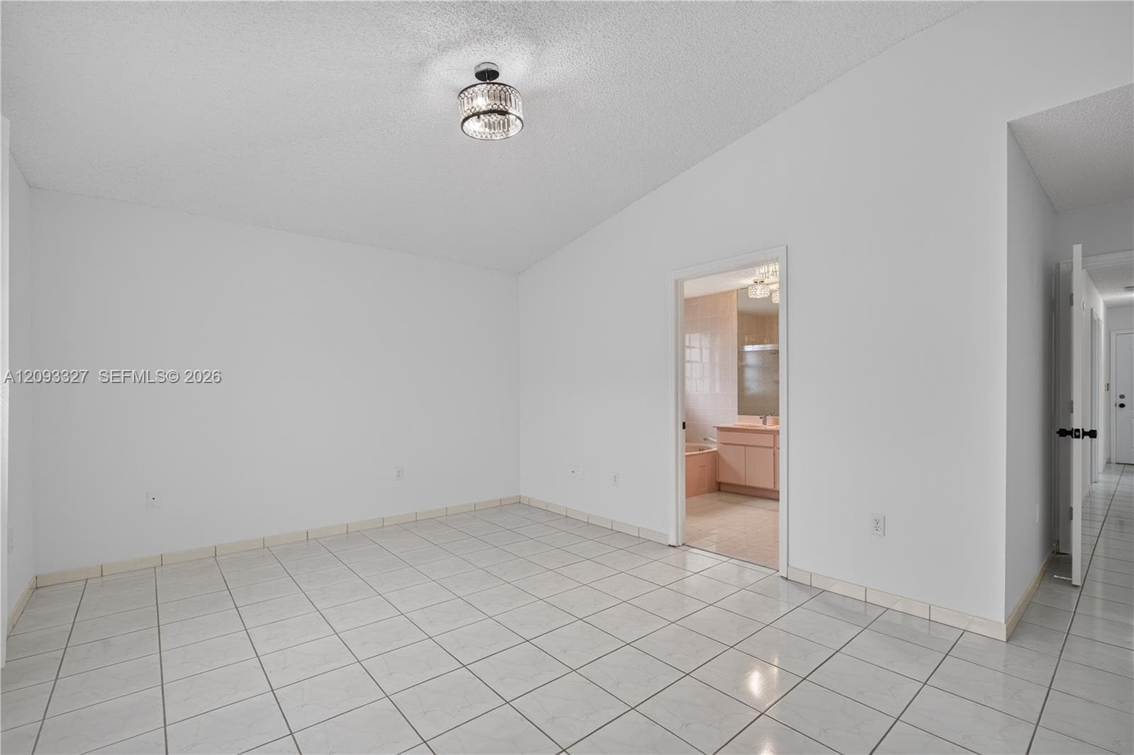 Room featuring high, vaulted ceilings, neutral wall tones, large-format tile flooring, and a contemporary crystal-accented semi-flush mount light fixture
