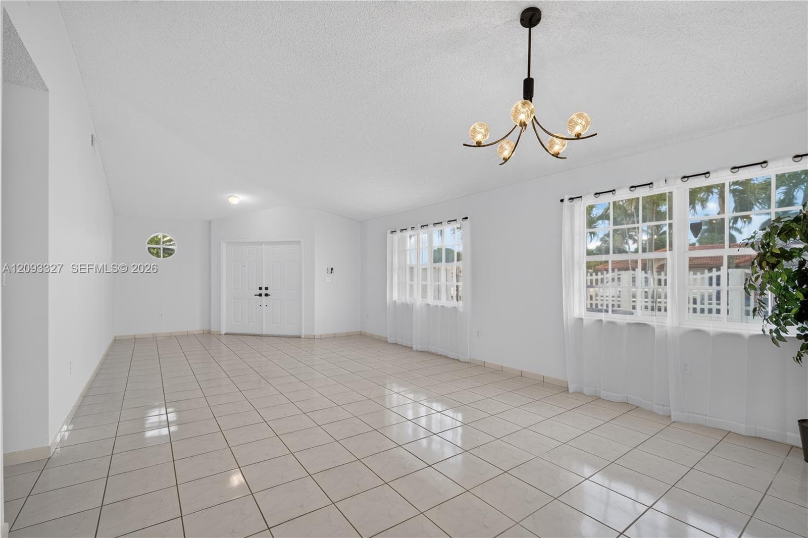 Neutral-toned tile flooring, double-entry front doors, multi-paned windows, and a multi-arm modern light fixture