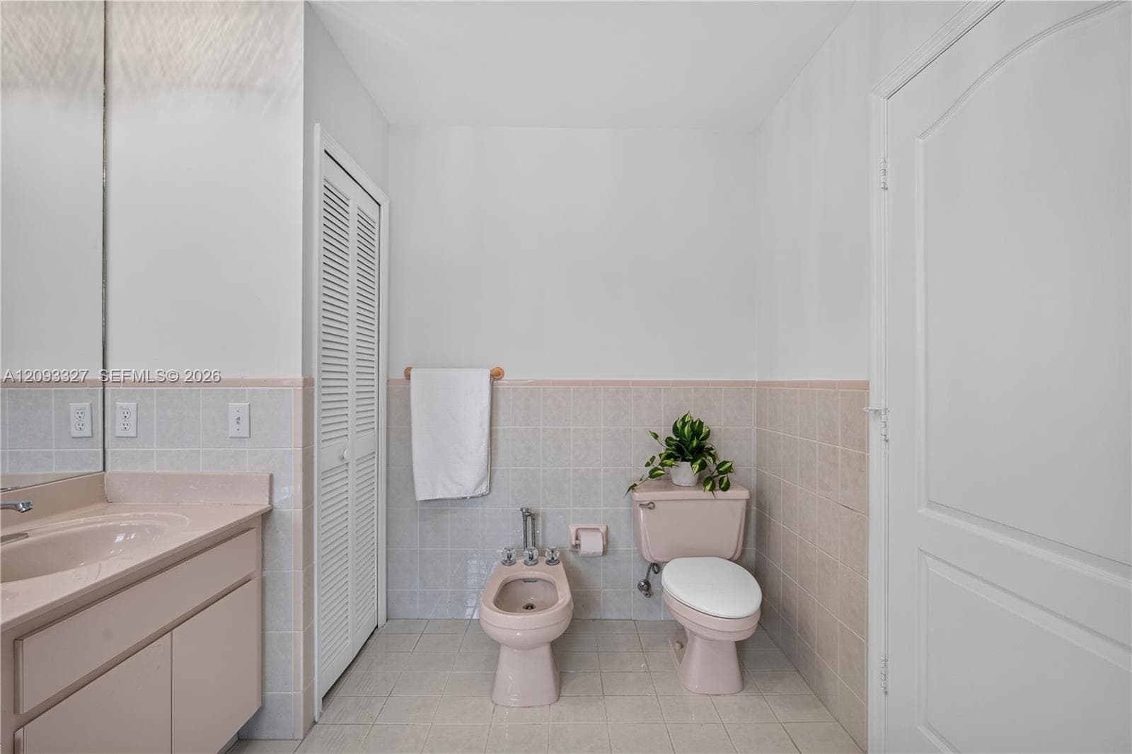 Bathroom featuring ceramic wall and floor tiling, integrated vanity, bidet, and two-door louvered closet