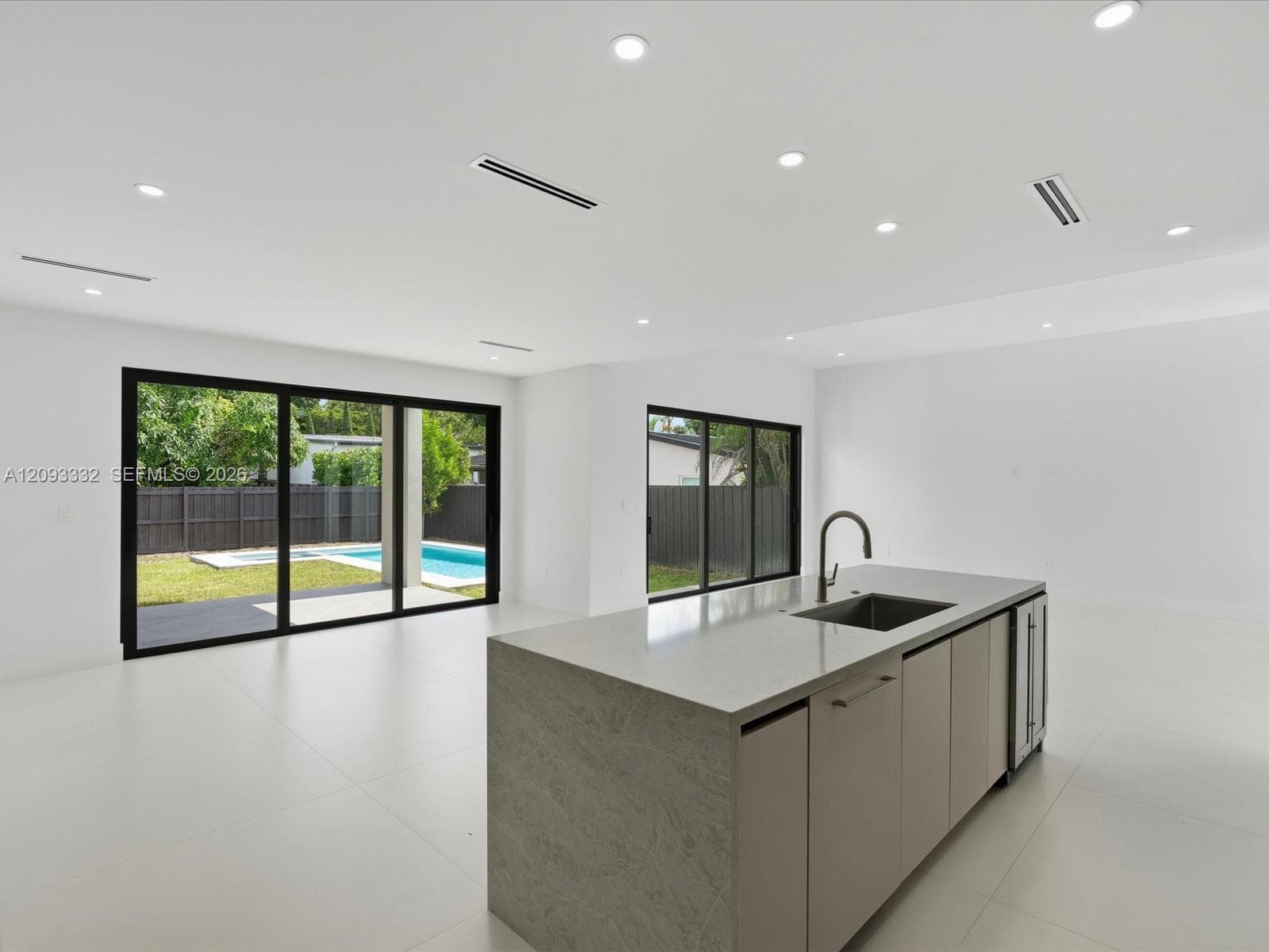 Open-concept interior featuring an expansive kitchen island with stone-finish countertops, undermount sink, and integrated beverage refrigeration