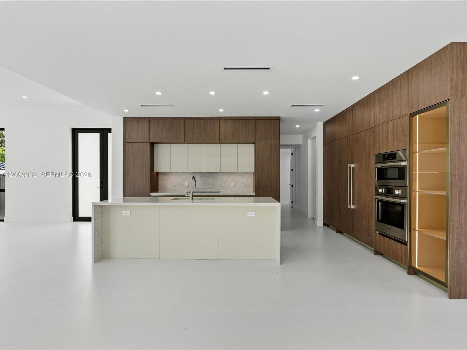 Kitchen featuring wood-finish cabinetry, central island with stone-surface countertop, built-in double wall oven, integrated refrigerator paneling, and recessed ceiling lighting