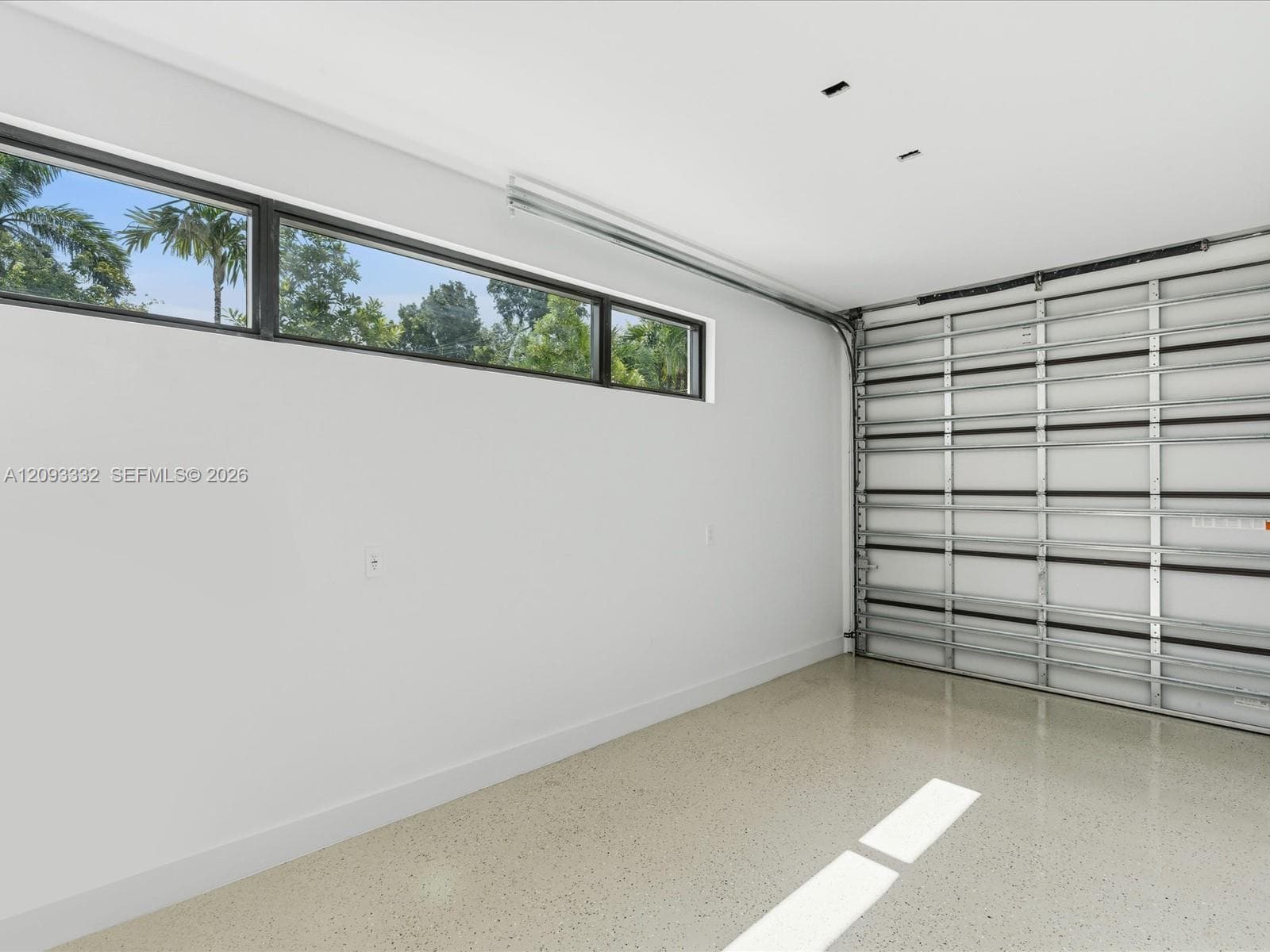 Finished garage featuring epoxy flooring, horizontal clerestory windows, and a metal sectional overhead door