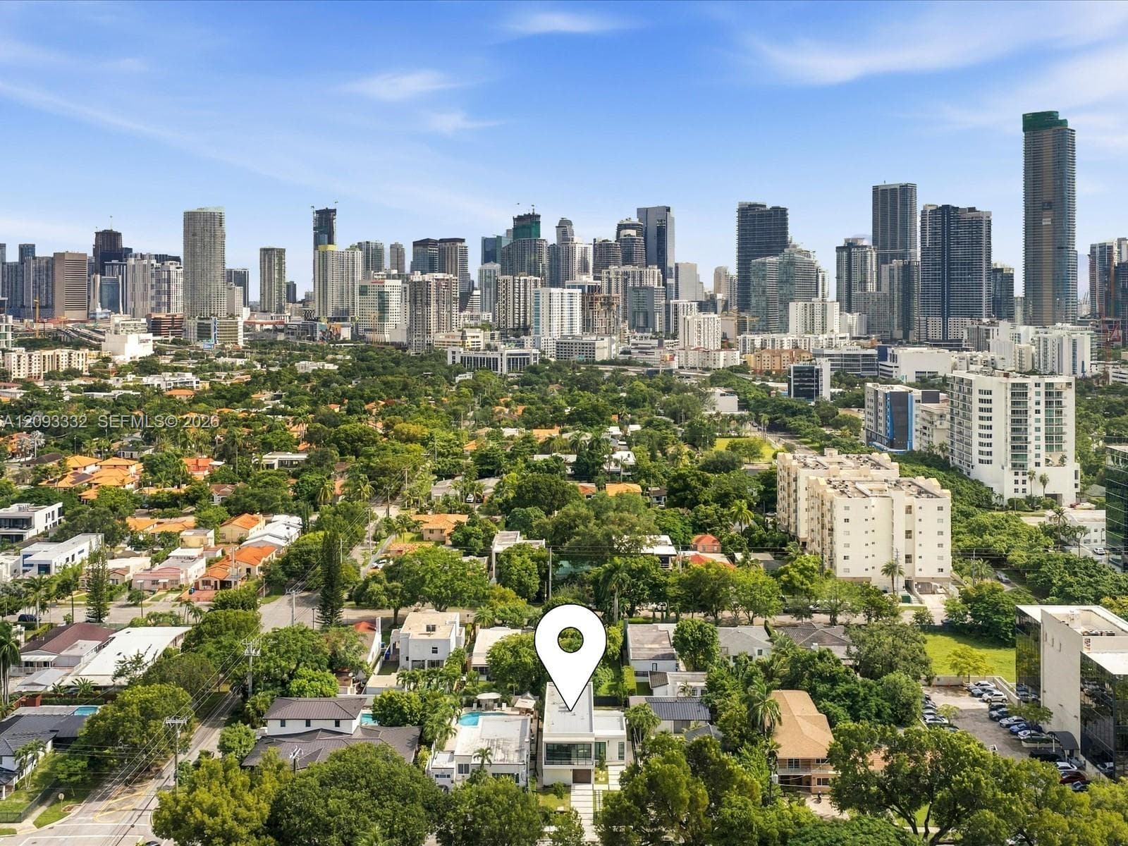 Aerial perspective showcasing a multi-story residence with a flat roofline and a swimming pool, set within a residential area featuring mature trees and a metropolitan skyline