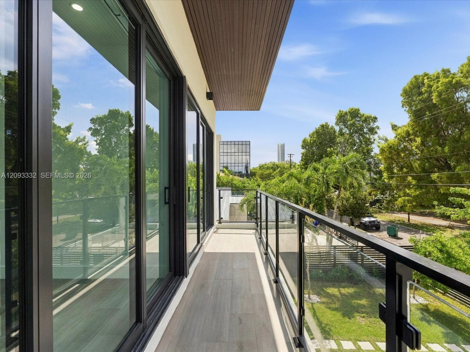 Balcony featuring a glass panel railing, wood-finish flooring, recessed ceiling lighting, and floor-to-ceiling glass sliding doors
