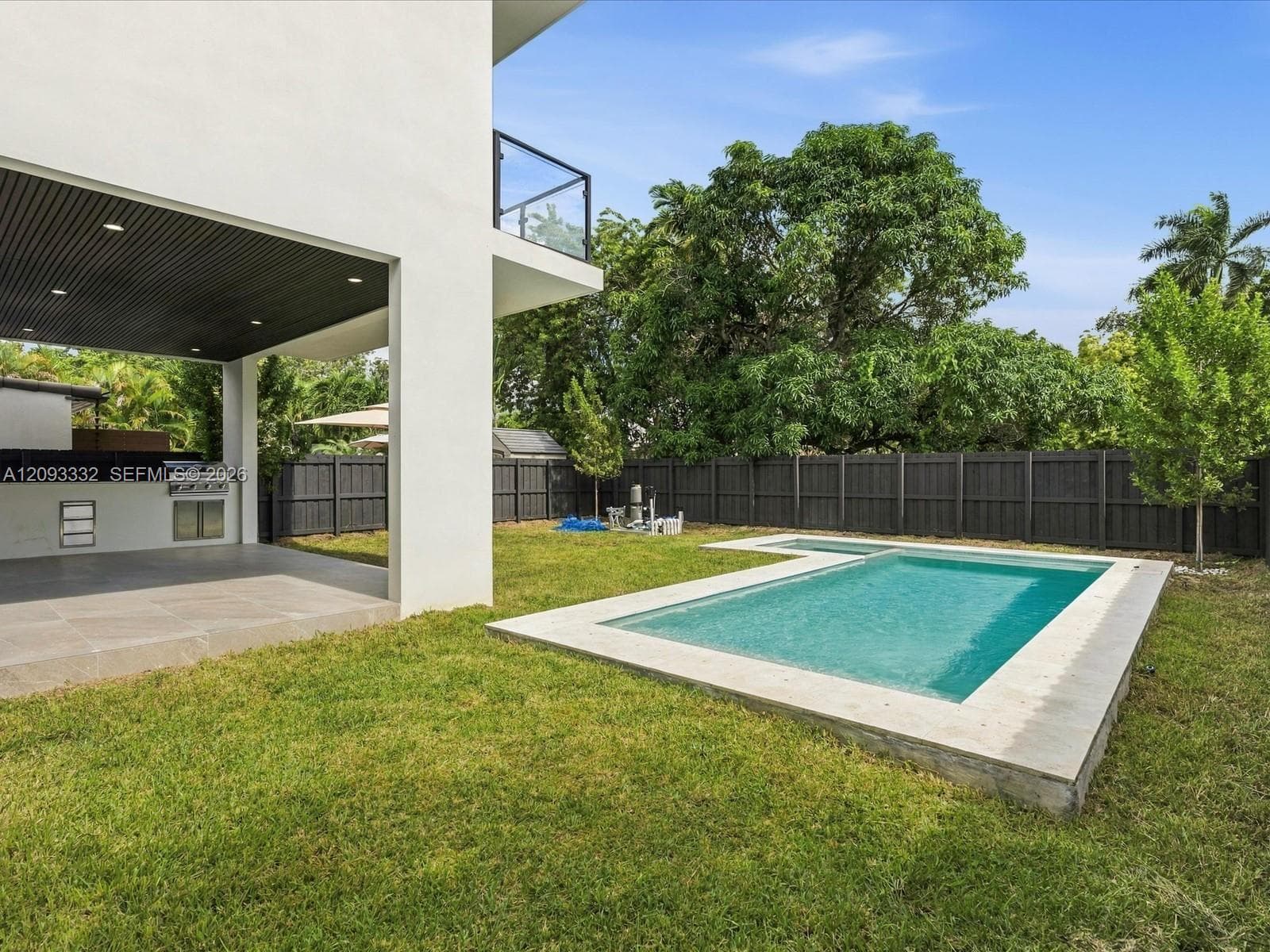 Backyard featuring a swimming pool with stone coping, covered patio with recessed lighting, built-in outdoor grill, and perimeter privacy fencing