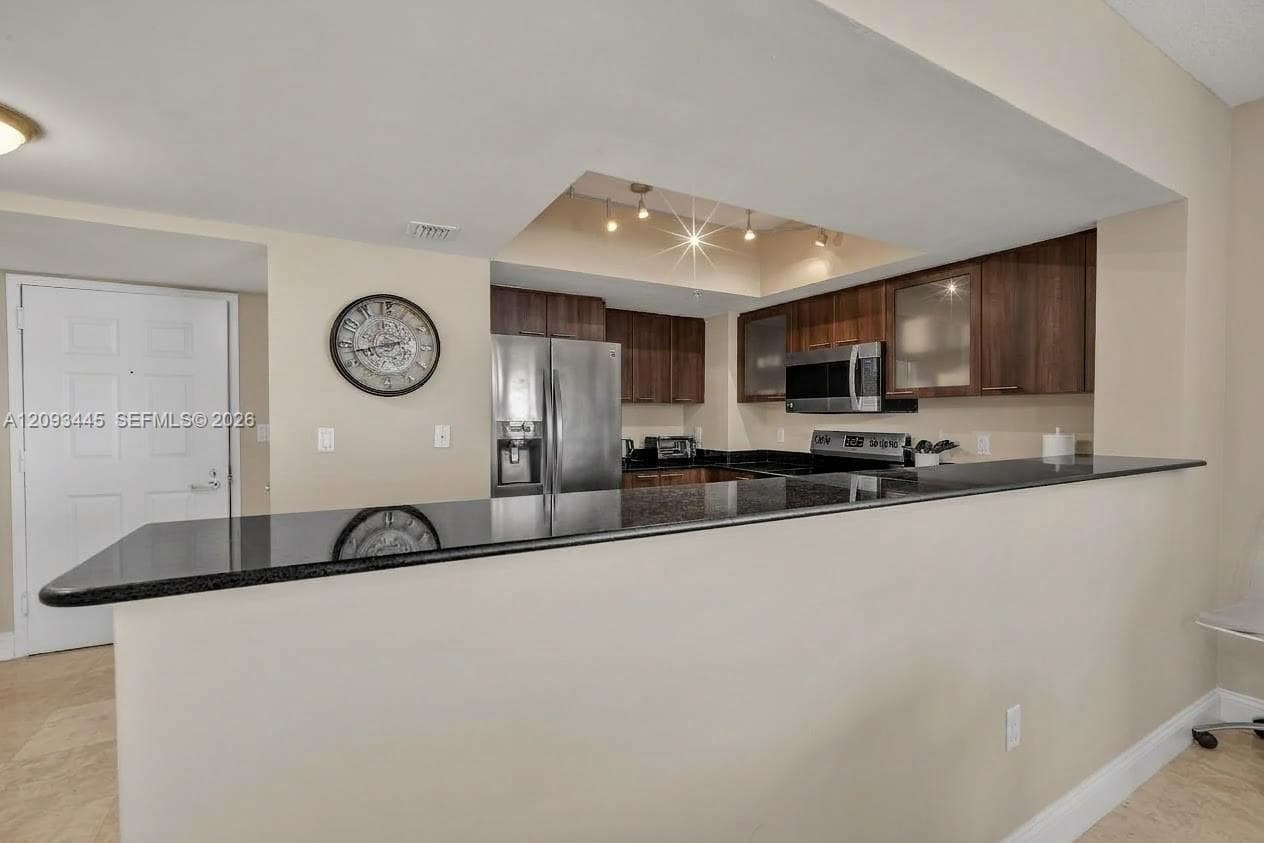 Kitchen cabinets modernized by A.I  Kitchen featuring dark wood-finish cabinetry, black countertops, stainless steel appliances, and recessed lighting