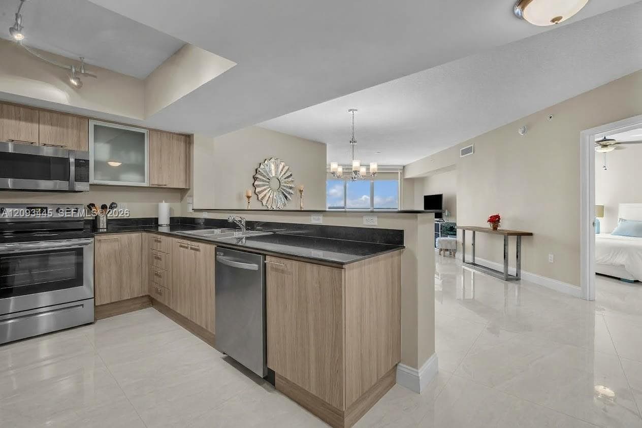Kitchen cabinets modernized by A.I  Kitchen featuring stainless steel appliances, wood-finish cabinetry, dark countertops, and tile flooring