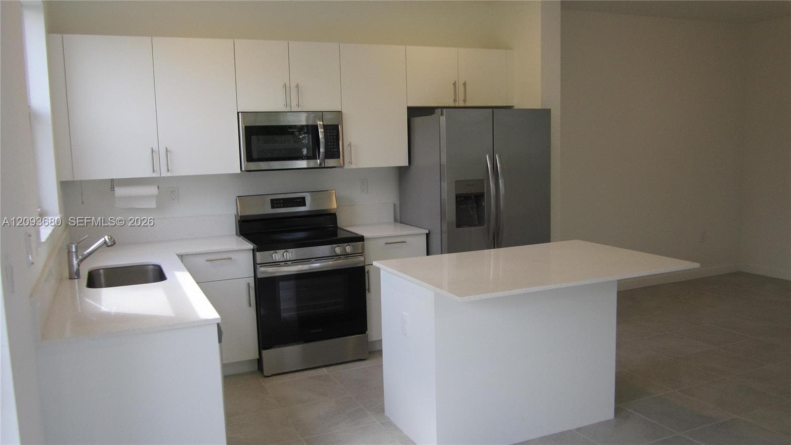 Kitchen featuring white cabinetry, solid-surface countertops, a center island, stainless steel appliances, and tiled flooring