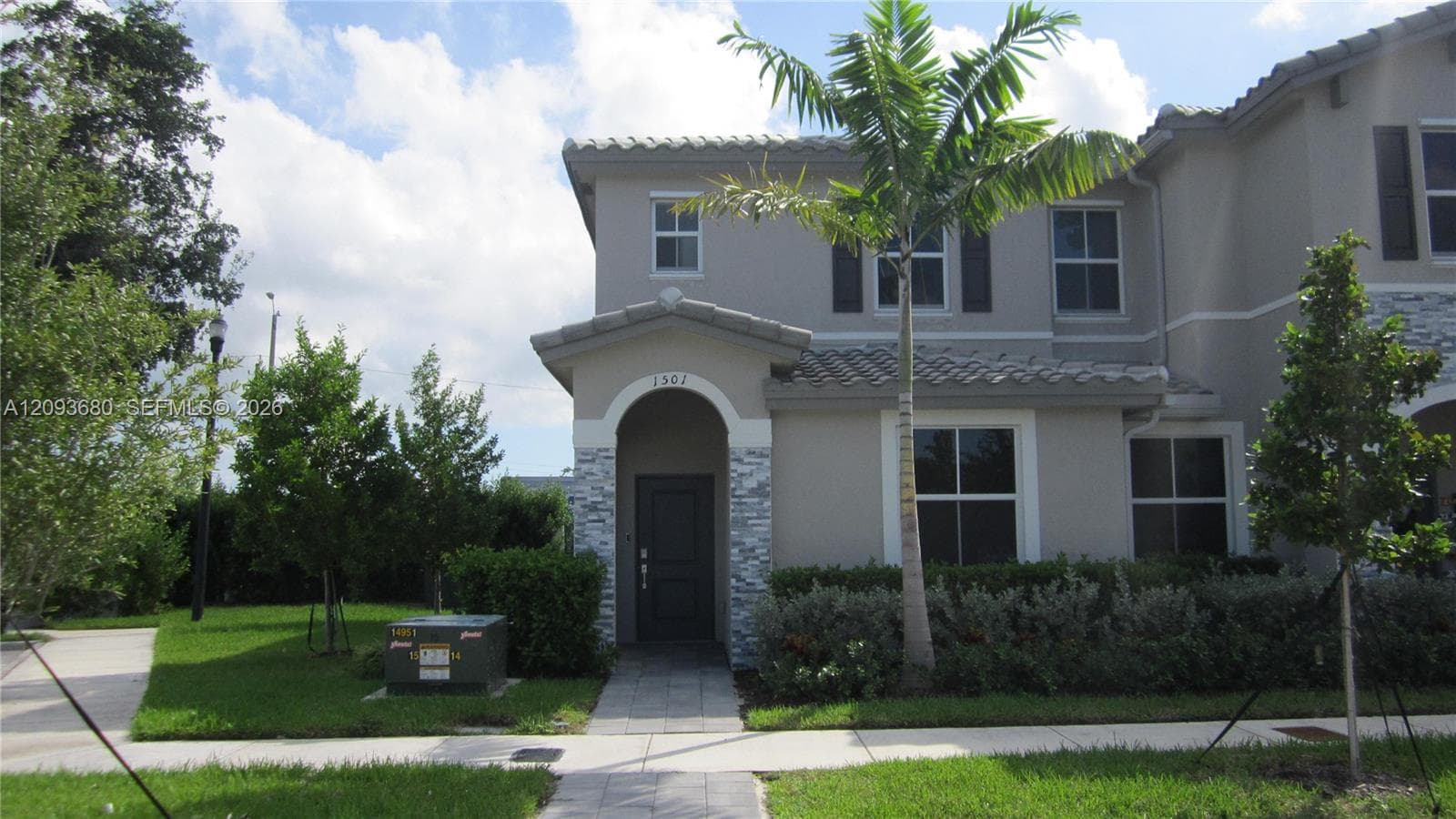 Two-story stucco exterior featuring a covered entryway, decorative stone veneer detailing, arched architectural accents, and a tile roof