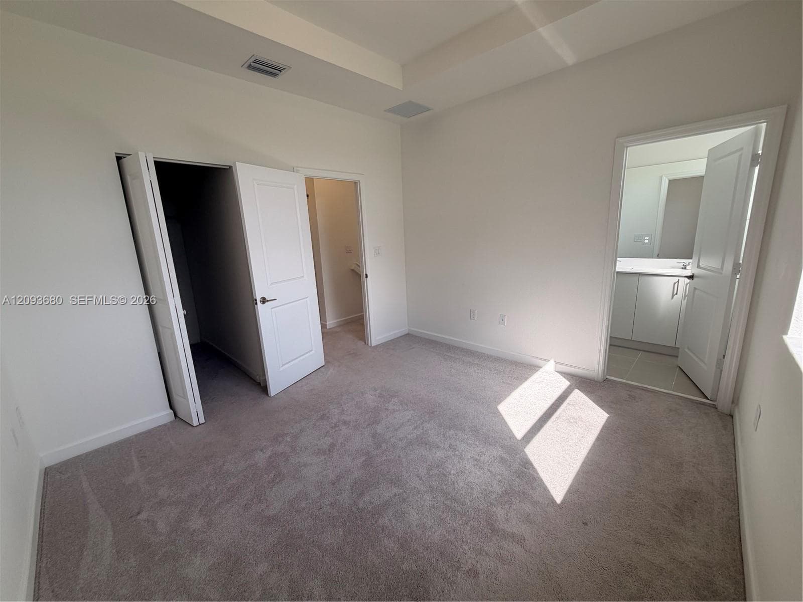 Neutral-toned carpeting, tray ceiling with recessed lighting, and interior panel doors