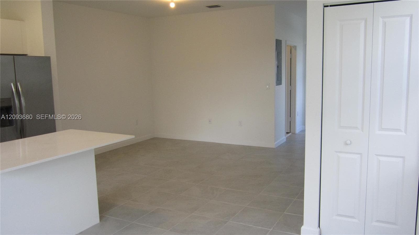 Interior space featuring neutral tile flooring, a kitchen island with a white countertop, and a white bi-fold closet door