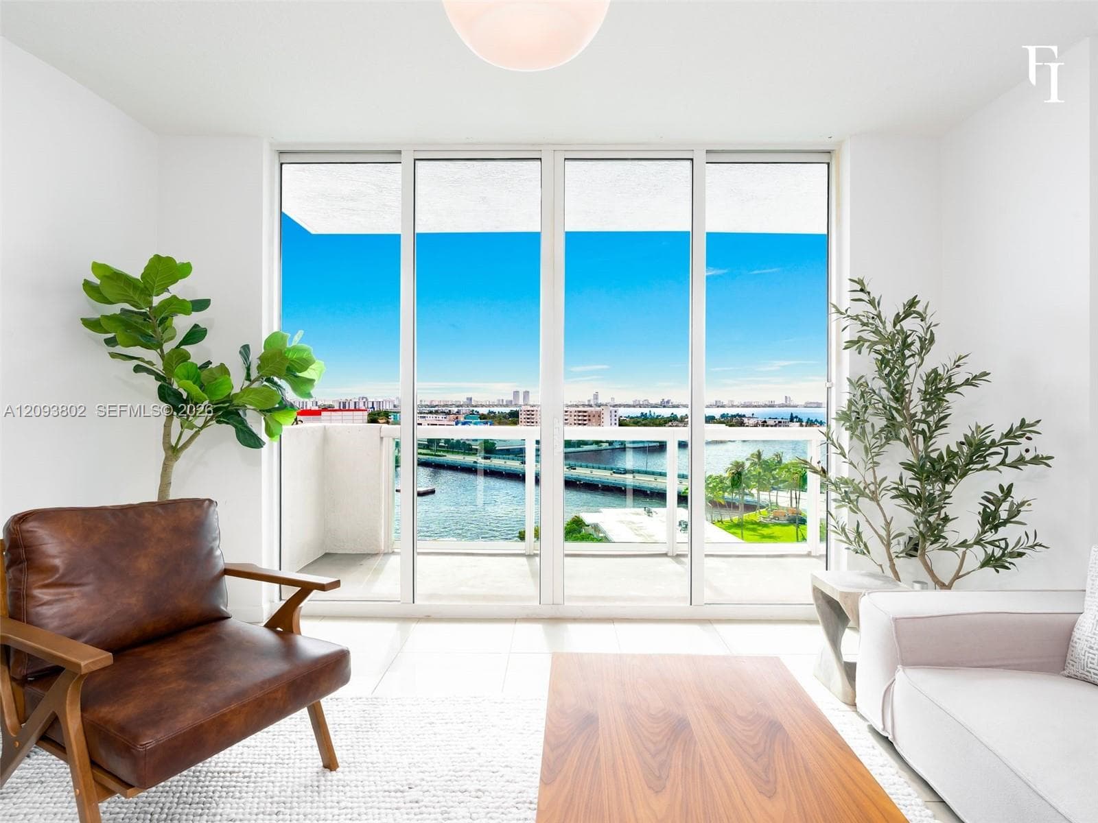 Floor-to-ceiling glass panel doors, white tiled flooring, and a glass-railed balcony featuring coastal water and cityscape scenery