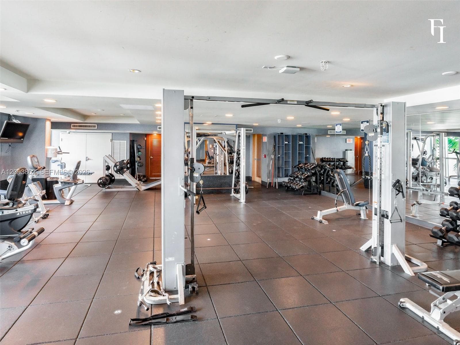 Fitness center featuring rubberized flooring, recessed lighting, expansive mirrored walls, and built-in storage cubbies