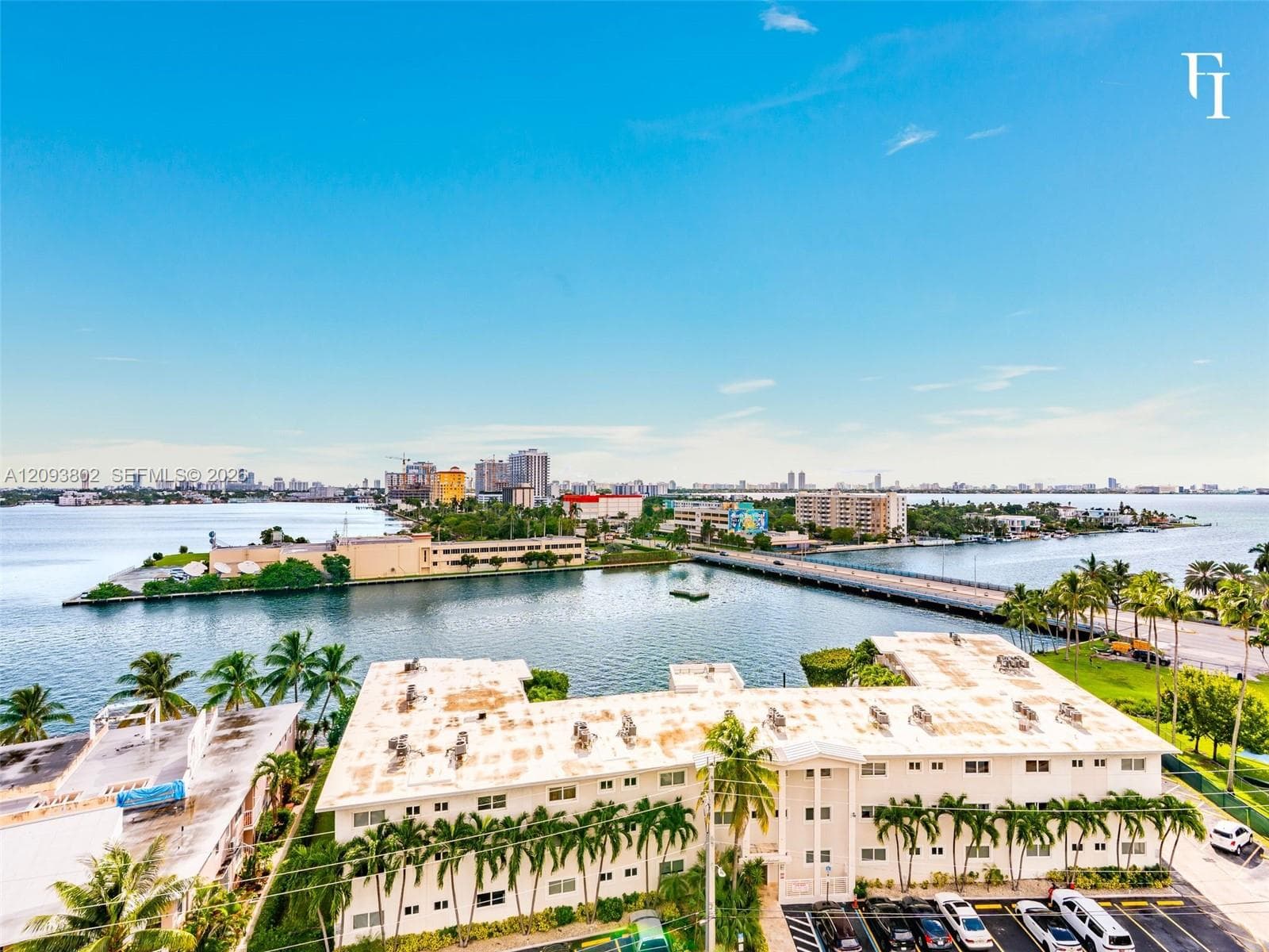 Waterfront property featuring panoramic bay scenery, mature palm trees, exterior parking, and proximity to urban infrastructure