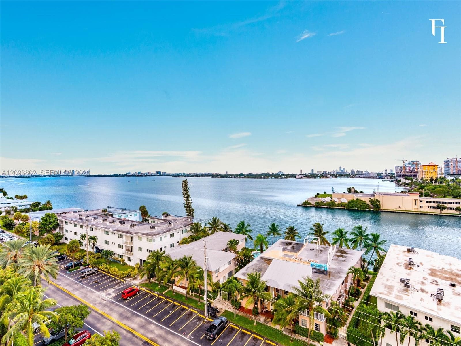 Aerial perspective featuring expansive coastal waterfront, mature palm trees, and established building exteriors