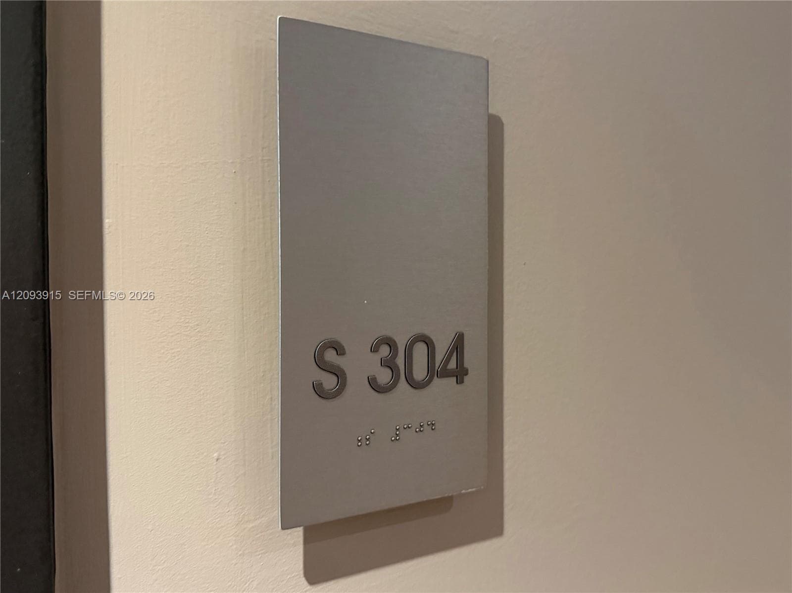 Brushed metal signage featuring raised alphanumeric character and tactile braille lettering