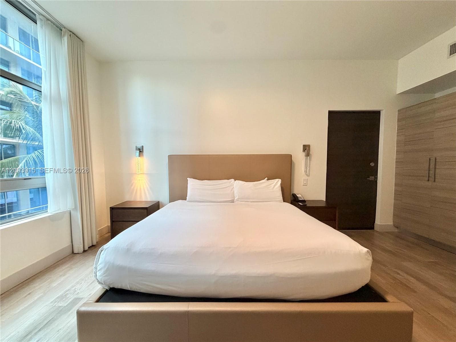 Floor-to-ceiling windows with integrated drapery, wood-finish flooring, built-in cabinetry, and wall-mounted light fixtures